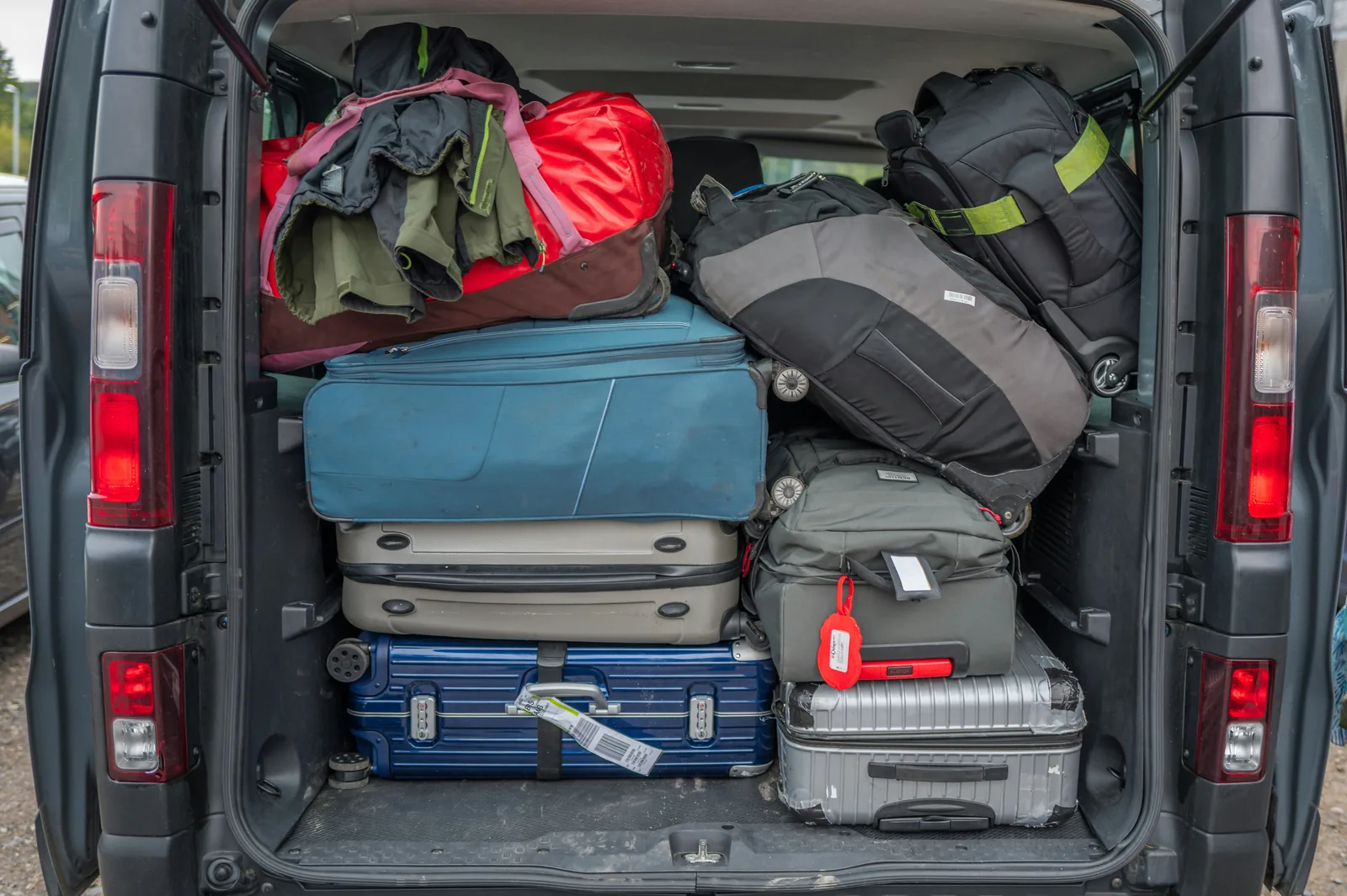 The open rear doors of a van with its load space packed to the roof with suitcases and holdalls