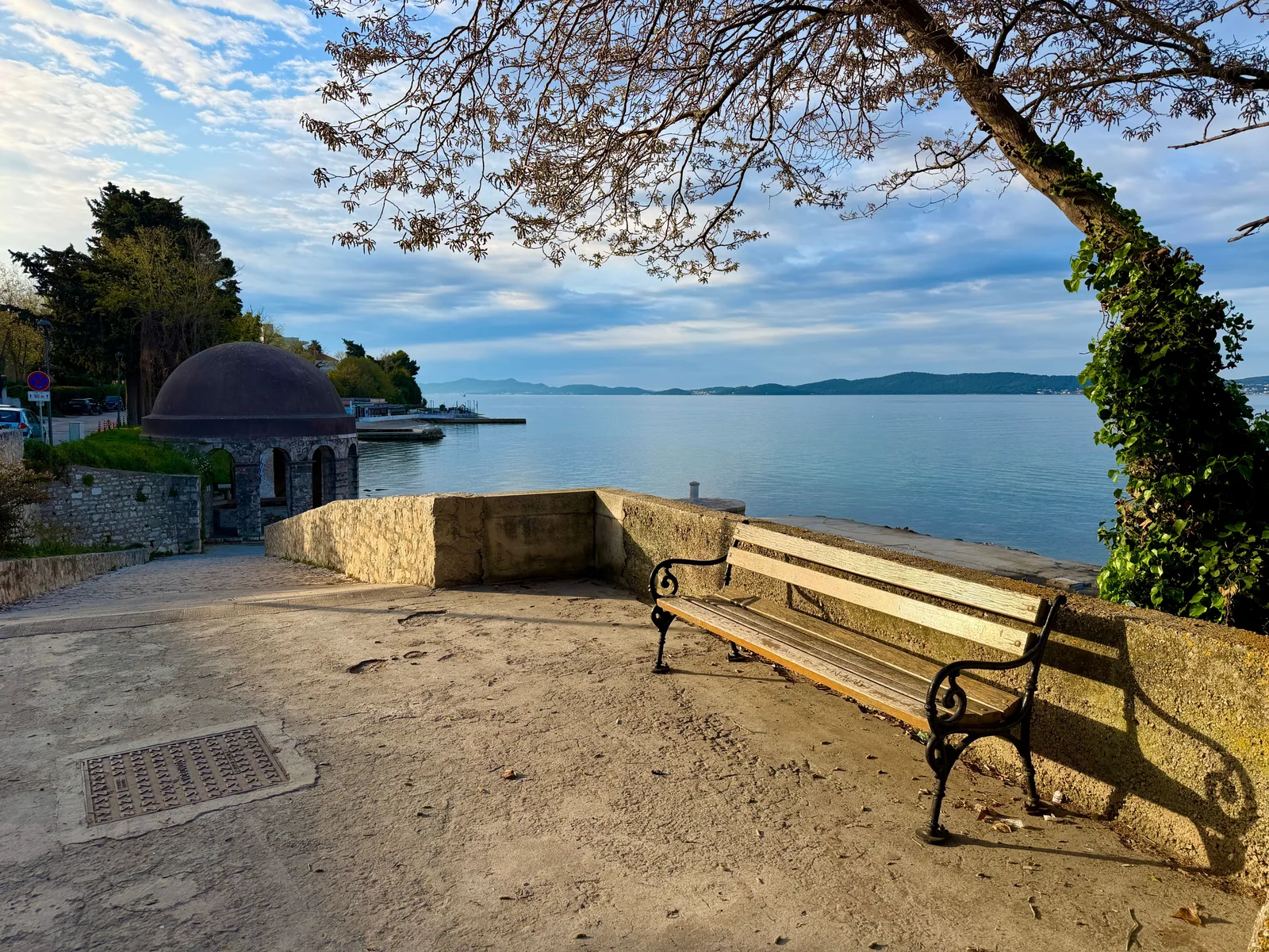 Eine Bank auf einer Uferpromenade mit Blick auf die Adria